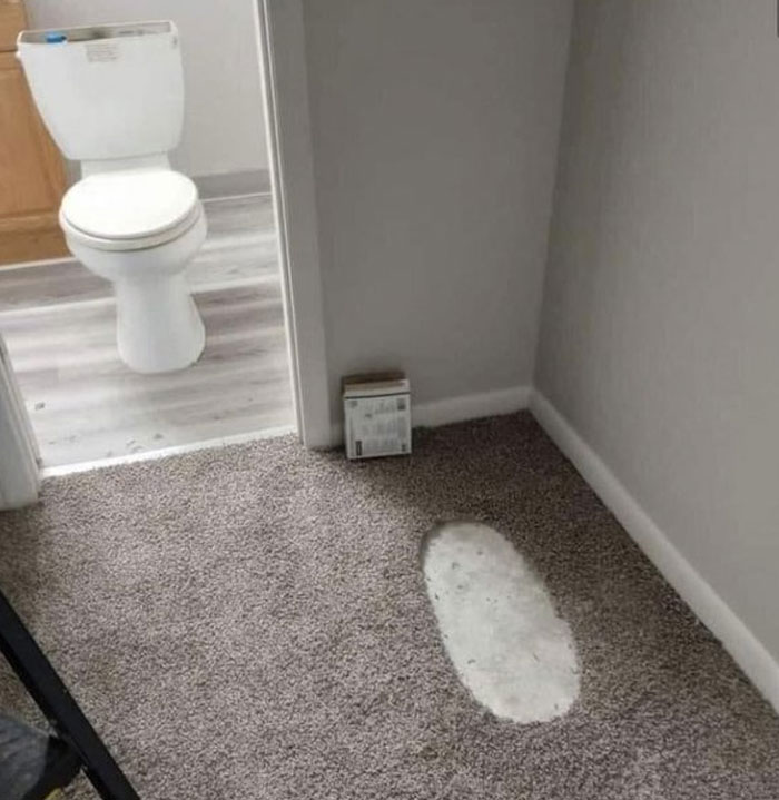 Carpet installation fail near bathroom door showing a cutout patch exposing concrete floor, a design and architecture nightmare. Carpet installation fail near bathroom door showing a cutout patch exposing concrete floor, a design and architecture nightmare.