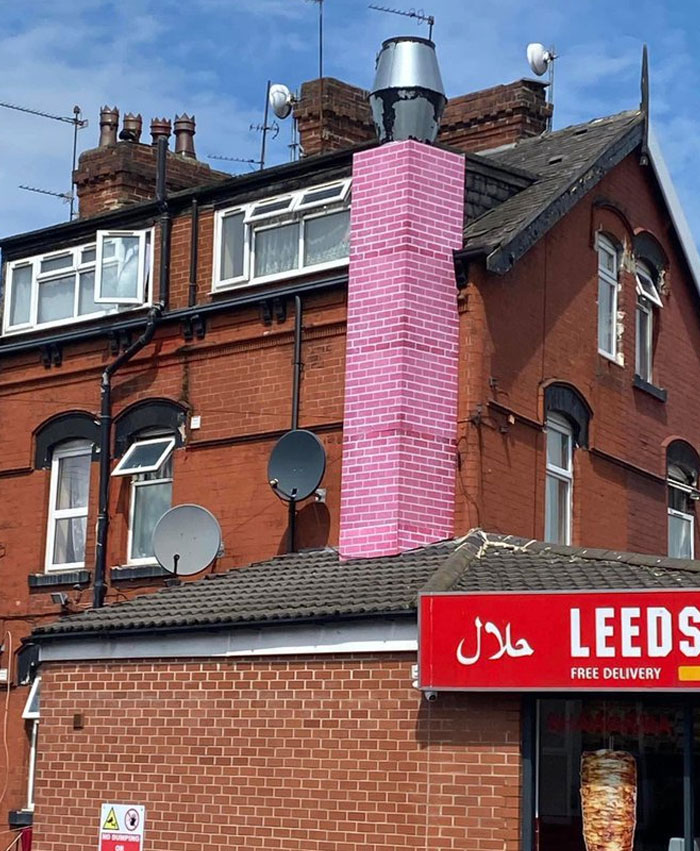 Pink brick chimney stands out on a traditional red brick building, showcasing a design and architecture nightmare example.