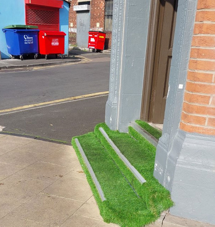 Steps covered with artificial grass in front of a building, illustrating a design and architecture nightmare example.