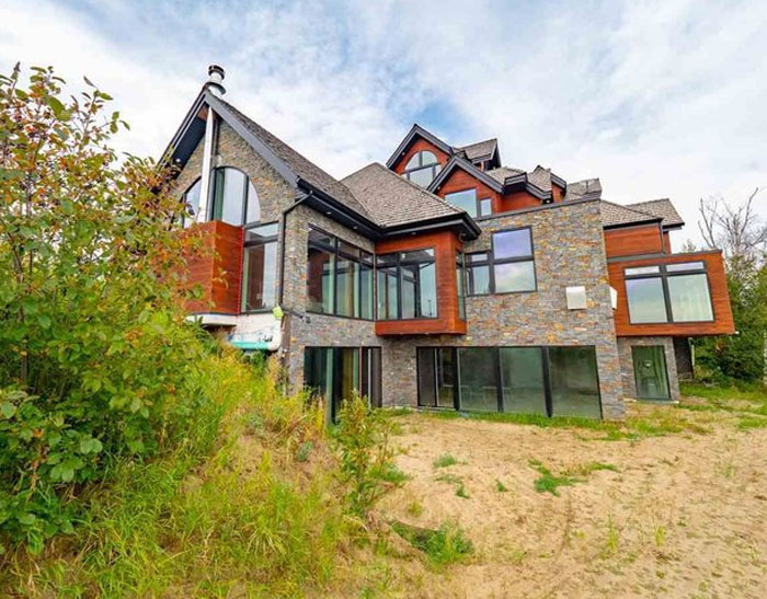Modern house with large glass windows and stone facade, a design and architecture nightmare showing poor common sense.