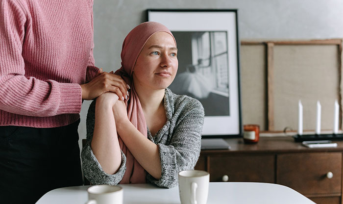 Woman wearing a headscarf looking hopeful while another person offers comfort, illustrating medical bills support and family trust issues. Woman wearing a headscarf looking hopeful while another person offers comfort, illustrating medical bills support and family trust issues.
