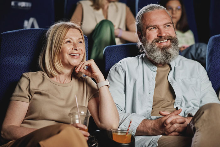 Couple enjoying a theatre show together, smiling and relaxed, representing Pregnant Daughter Cancel Theatre atmosphere.