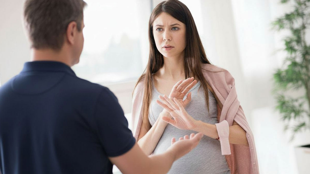Pregnant wife looking frustrated and talking to her husband who listens, showing tension in a home setting.