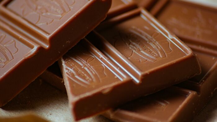 Close-up of broken milk chocolate pieces with smooth texture, highlighting relationship gestures and princess treatment themes.