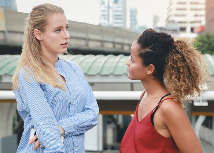 Two women outdoors engaged in deep conversation demonstrating psychological tricks people use on themselves and others.
