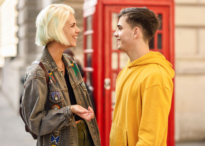 Two young people smiling and talking on the street, illustrating psychological tricks people use on themselves and others.