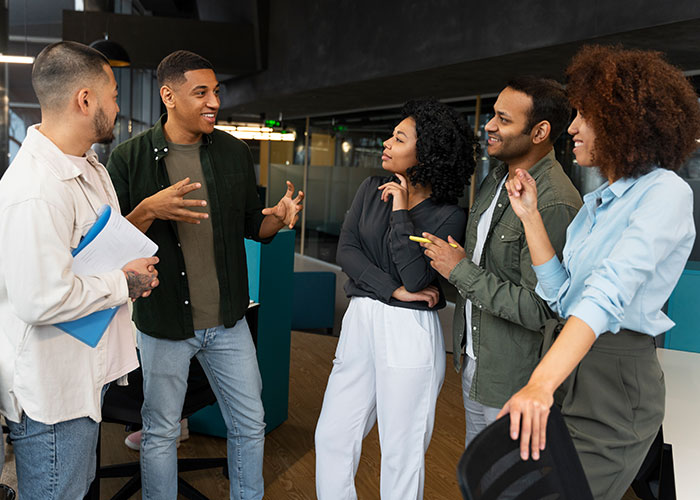 Group of diverse young adults engaged in a conversation using psychological tricks in a modern office setting.