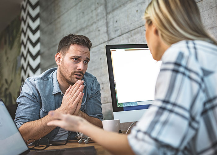 Man and woman in discussion at a desk demonstrating psychological tricks used on themselves and others during conversation.