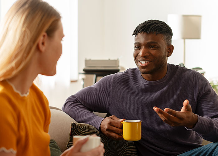 Two people having a friendly conversation over coffee, illustrating psychological tricks people use on themselves and others.