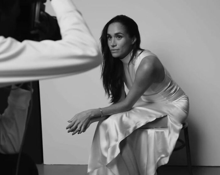 Meghan Markle in a makeup-free cover photo sitting in a white dress during a black and white photoshoot session. Meghan Markle in a makeup-free cover photo sitting in a white dress during a black and white photoshoot session.