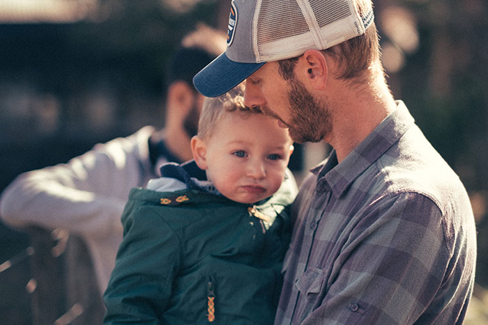 Father holding young child outdoors, capturing a moment of connection reflecting parents and children unhappiness reasons.