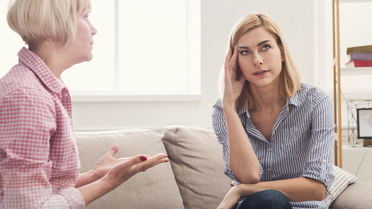 Mother and adult daughter having a tense conversation on a couch, illustrating parents and children unhappy moments.