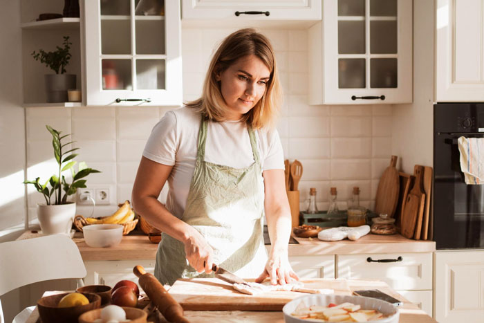 Woman in a kitchen baking cookies, perfecting secret recipe, highlighting cookies and family baking rivalry theme.