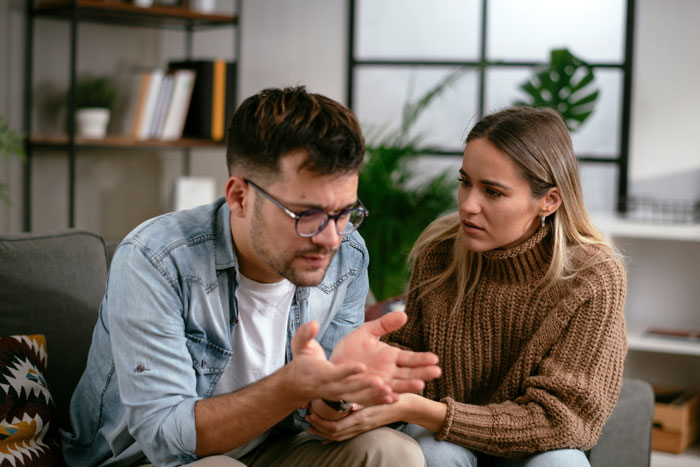Man refuses babysitting on vacation, woman looks concerned during serious conversation in cozy living room. Man refuses babysitting on vacation, woman looks concerned during serious conversation in cozy living room.