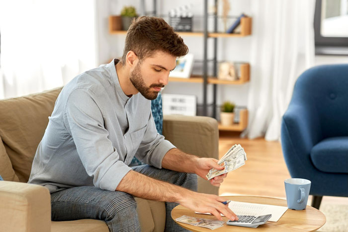 Young man counting money at home, considering expenses related to inheritance and financial decisions about BBL and college. Young man counting money at home, considering expenses related to inheritance and financial decisions about BBL and college.