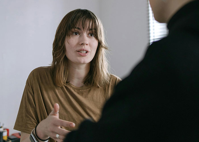 Young woman refusing to quit job after husband’s promotion, engaged in serious discussion about gender roles.