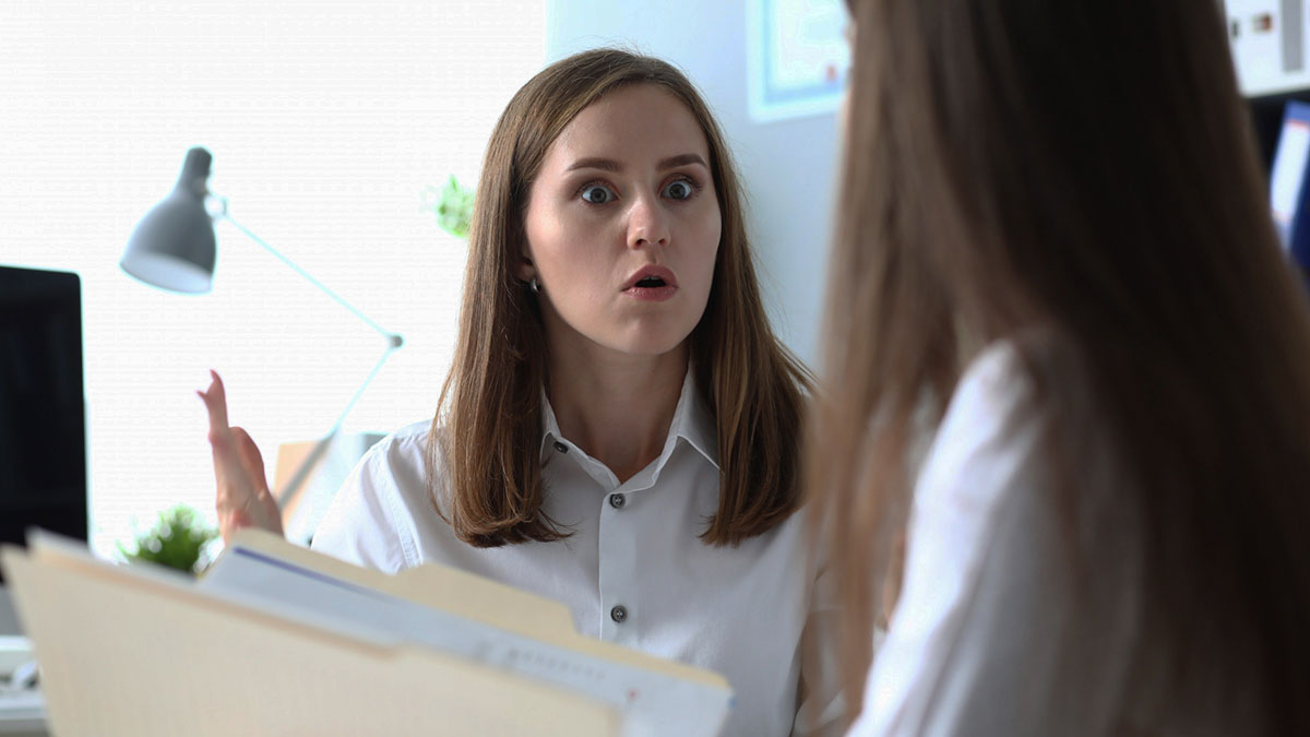 Analyst visibly upset while talking to colleague in an office, highlighting HR conflict over free labor and workplace duties.