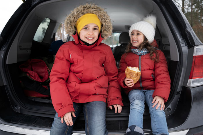 Two children in winter jackets sitting in the back of a car representing a happy family after abandonment reunion. Two children in winter jackets sitting in the back of a car representing a happy family after abandonment reunion.