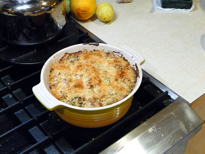 Baked dish on stovetop with browned topping, lemons and an orange in the background, illustrating people's lies getting out of hand.