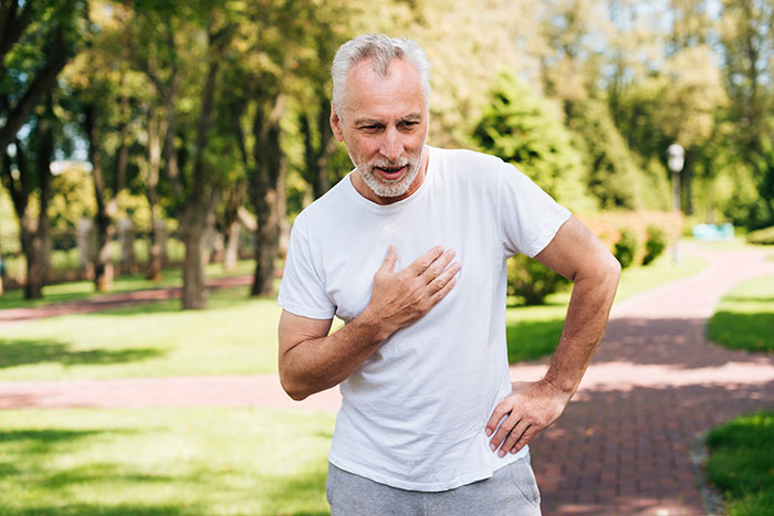 Older man experiencing chest pain outdoors, illustrating consequences of people’s lies getting out of hand.