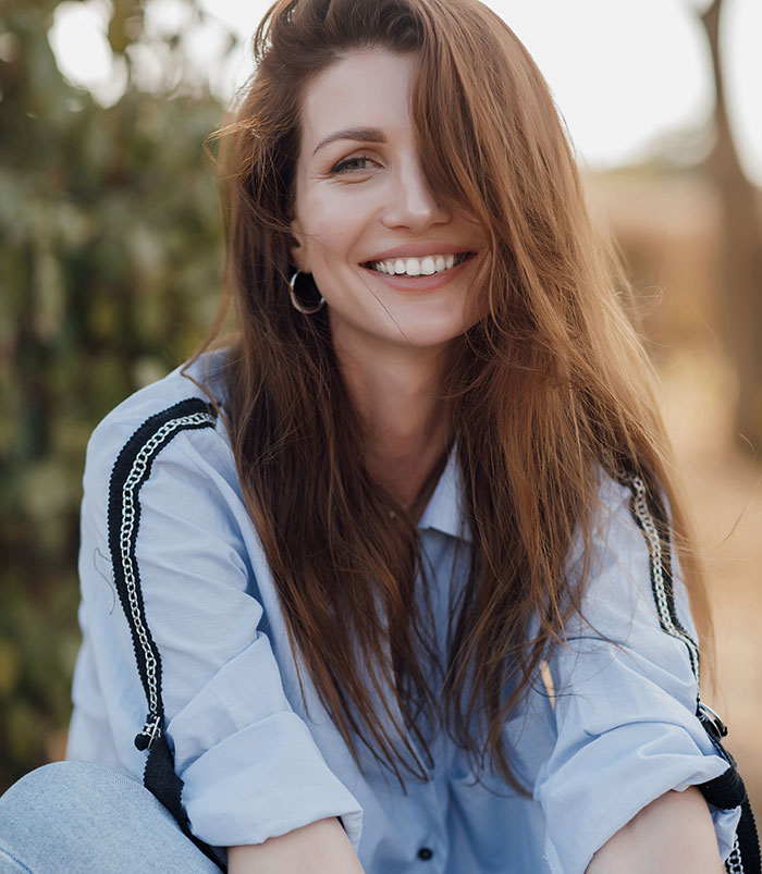 Young woman smiling outdoors wearing a blue shirt, representing times people's lies got out of hand and impacted lives.