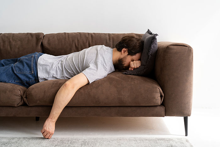 Man lying face down on a brown couch looking stressed, illustrating how lies got out of hand and changed lives.