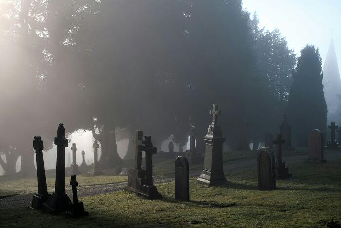 Foggy graveyard with numerous old tombstones and crosses, evoking a real-life horror story atmosphere.