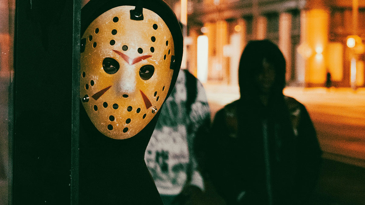 Person wearing a scary mask staring at the camera at night, illustrating the scariest things people have woken up to.
