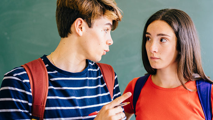 Two classmates having a serious conversation in a classroom, with expressions suggesting drama or tension. Two classmates having a serious conversation in a classroom, with expressions suggesting drama or tension.