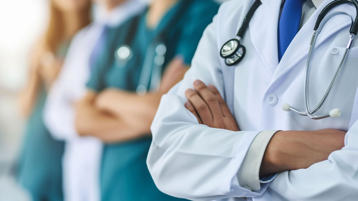 Group of seven doctors standing with arms crossed, wearing professional medical attire and stethoscopes.