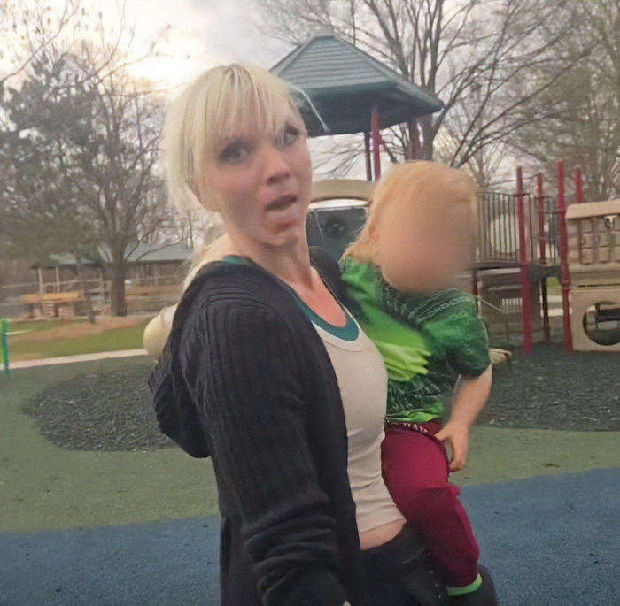 Woman involved in viral playground clash with autistic boy faces trial, holding child at park playground equipment. Woman involved in viral playground clash with autistic boy faces trial, holding child at park playground equipment.