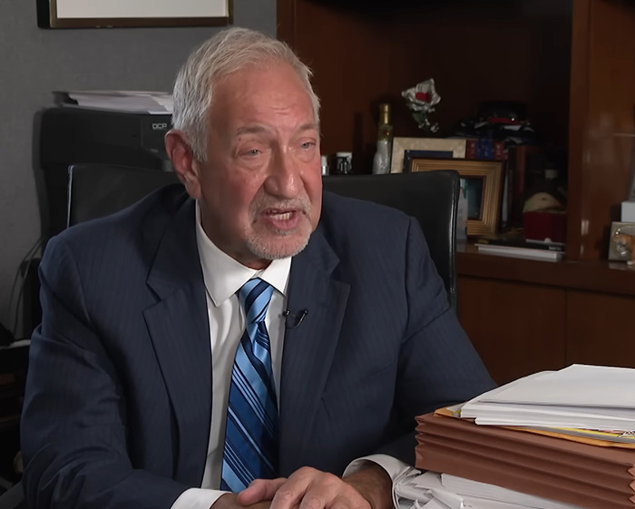 Man in a suit and striped tie speaking in an office, surrounded by folders and papers, discussing Michael Jackson allegations. Man in a suit and striped tie speaking in an office, surrounded by folders and papers, discussing Michael Jackson allegations.