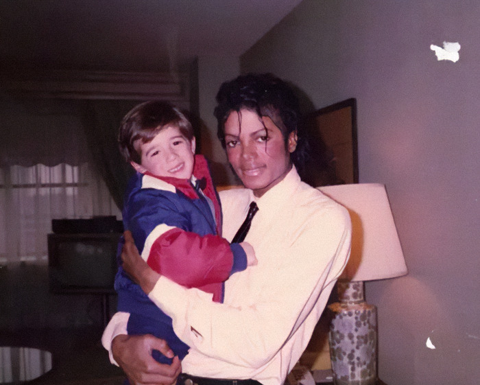 Michael Jackson holding a young child indoors, related to disturbing new sibling allegations amid biopic trailer release. Michael Jackson holding a young child indoors, related to disturbing new sibling allegations amid biopic trailer release.