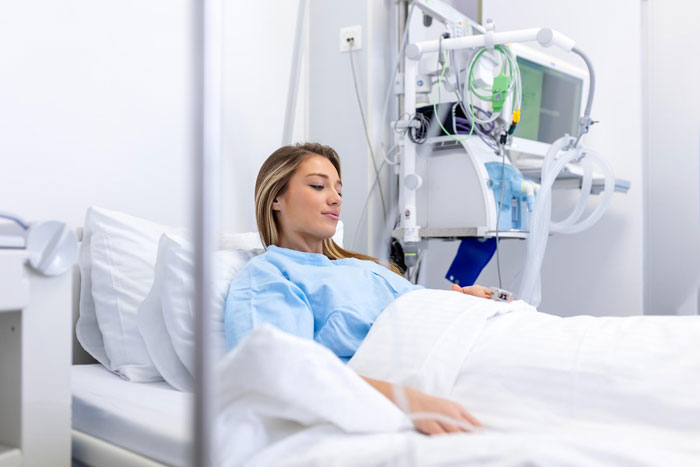 Woman in hospital bed looking thoughtful while medical equipment is beside her, relating to babysitting nephew conflict. Woman in hospital bed looking thoughtful while medical equipment is beside her, relating to babysitting nephew conflict.