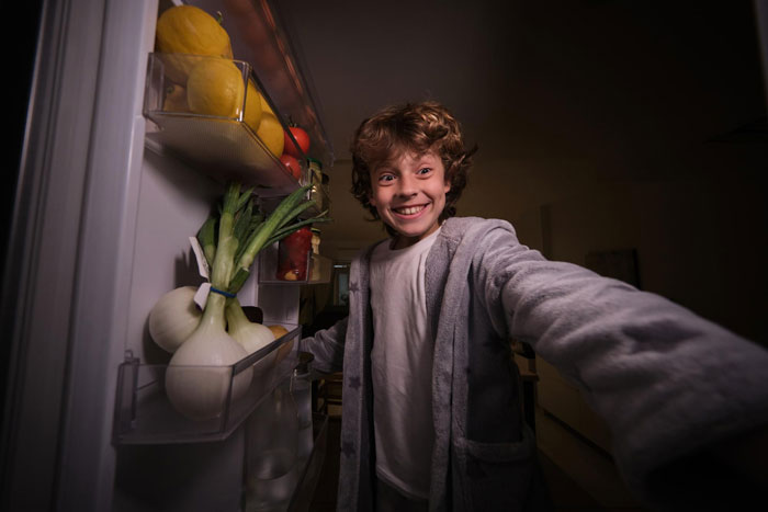 Smiling boy reaching into fridge, representing badly behaved nephew in a lady calls sis selfish cow babysitting dispute. Smiling boy reaching into fridge, representing badly behaved nephew in a lady calls sis selfish cow babysitting dispute.