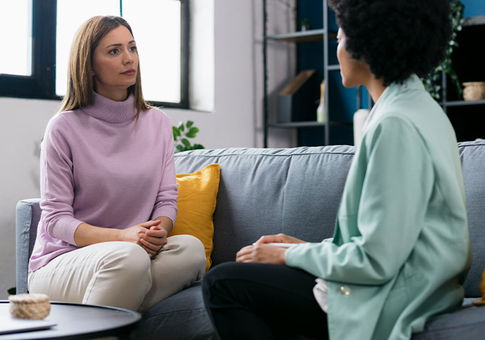 Two women having a serious conversation on a couch about charity and Christmas presents in a cozy living room. Two women having a serious conversation on a couch about charity and Christmas presents in a cozy living room.
