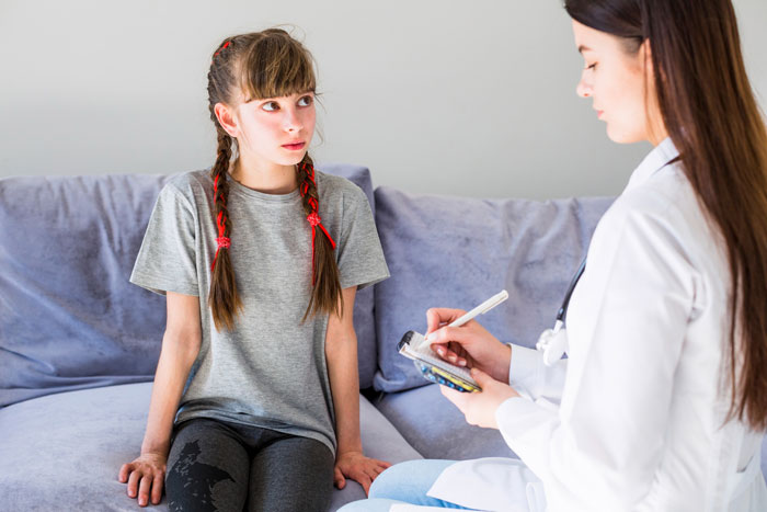 Teen girl with mental health struggles talking to female doctor in a consultation, feeling trapped and unheard at home.