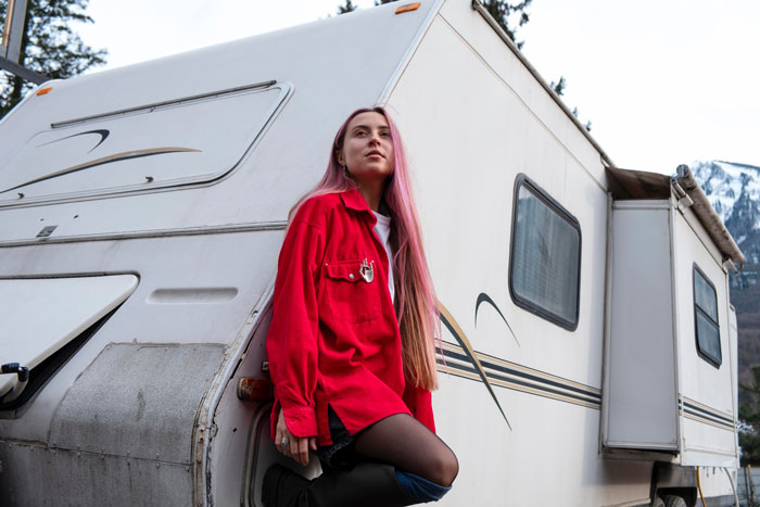 Woman with pink hair leaning against an old camper, representing woman wanting to charge sis clean-up fee after spotting roaches. Woman with pink hair leaning against an old camper, representing woman wanting to charge sis clean-up fee after spotting roaches.