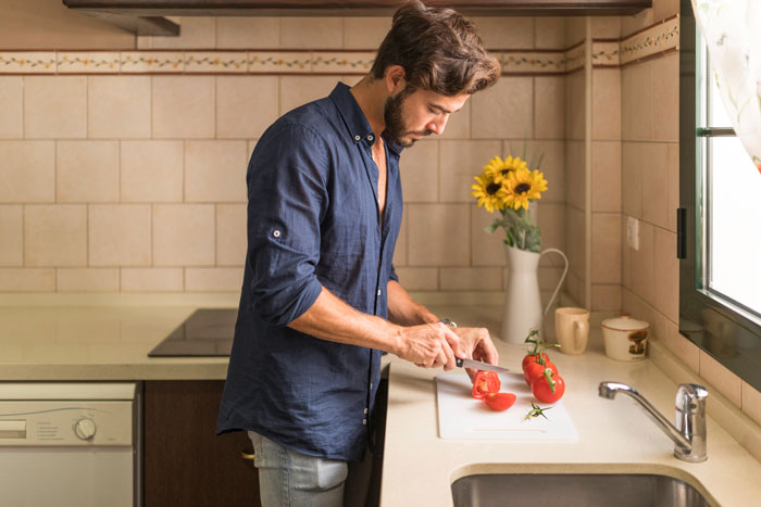 Man showing affection for his sick wife by preparing food in kitchen while sister looks on annoyed. Man showing affection for his sick wife by preparing food in kitchen while sister looks on annoyed.