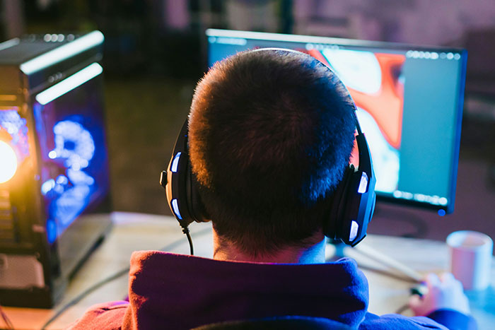 Person wearing headphones playing video games on a desktop computer, illustrating lies that affected people’s lives unexpectedly.