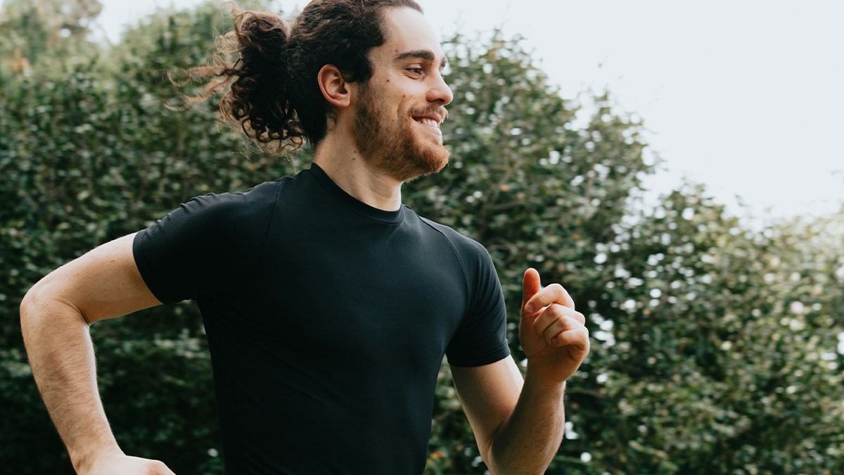 Man in black shirt jogging outdoors with greenery in background, reflecting on lies that affected peopleu2019s lives.