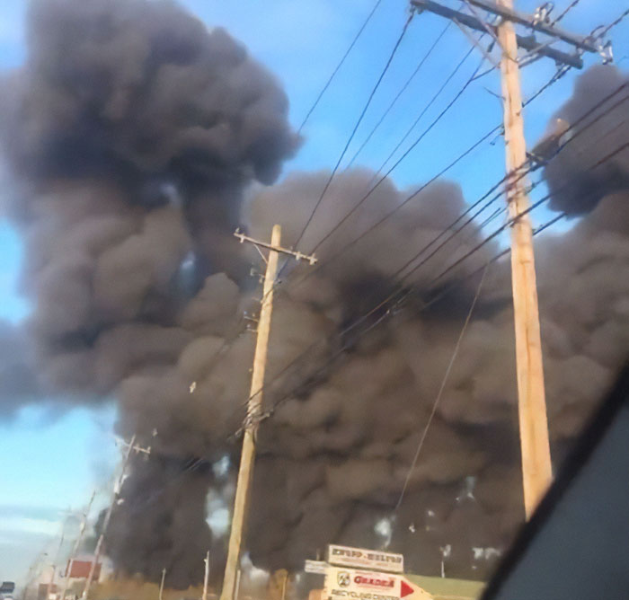 Thick black smoke rising from a UPS plane crash site with multiple casualties visible near power lines. Thick black smoke rising from a UPS plane crash site with multiple casualties visible near power lines.
