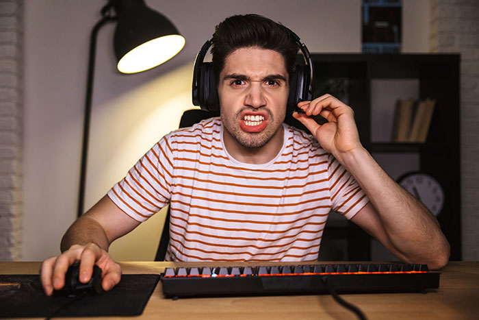 Teen with headphones frustrated at computer desk, reacting to breaking new chair one day after getting it.