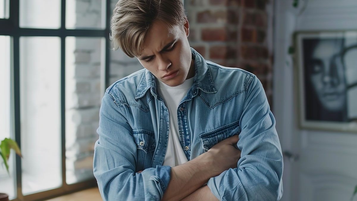 Teen male in a denim jacket holding his side in pain after a sprain and c*****d ribs during a family visit.