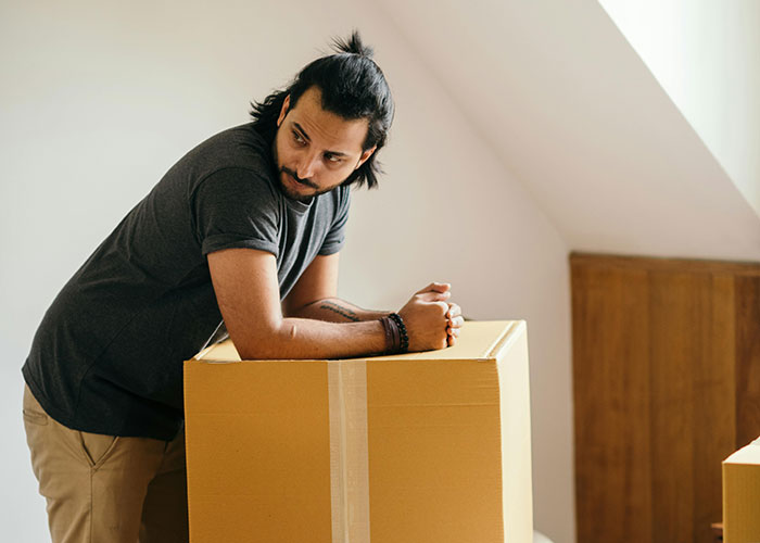 Man leaning on a cardboard box, looking thoughtful, representing a man done with stalkerish HOA president issues. Man leaning on a cardboard box, looking thoughtful, representing a man done with stalkerish HOA president issues.