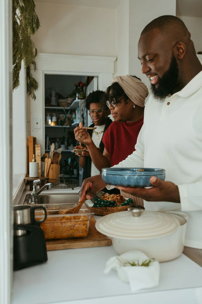 Three people enjoying homemade food together in a kitchen, highlighting positive stereotypes about various countries.