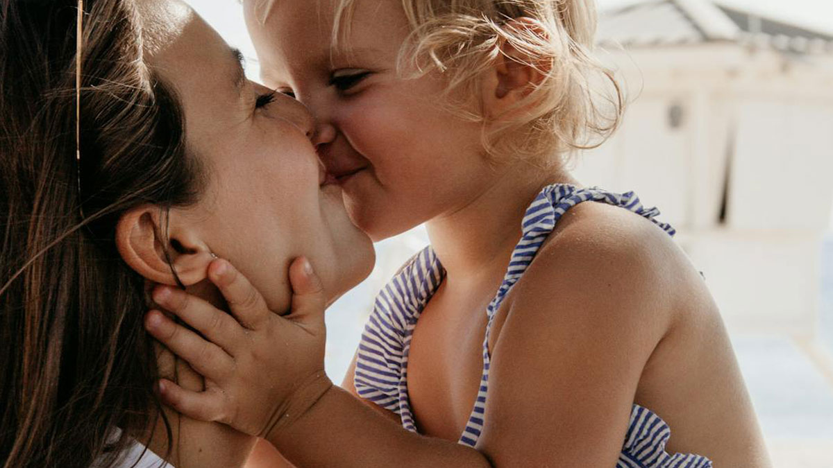 Child smiling toddler touching mother's face, capturing childhood habits and moments of affectionate bonding.
