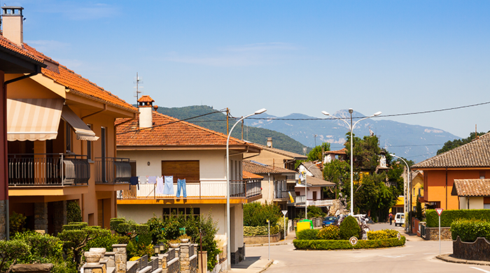 Quiet suburban neighborhood with houses and mountains in the distance, symbolizing siblings neglected and seeking reconnection.