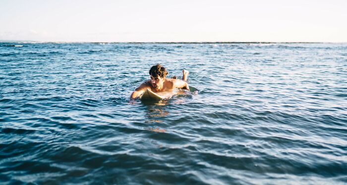 A young man swimming in the ocean representing unexpected moments and the craziest coincidences people experienced.