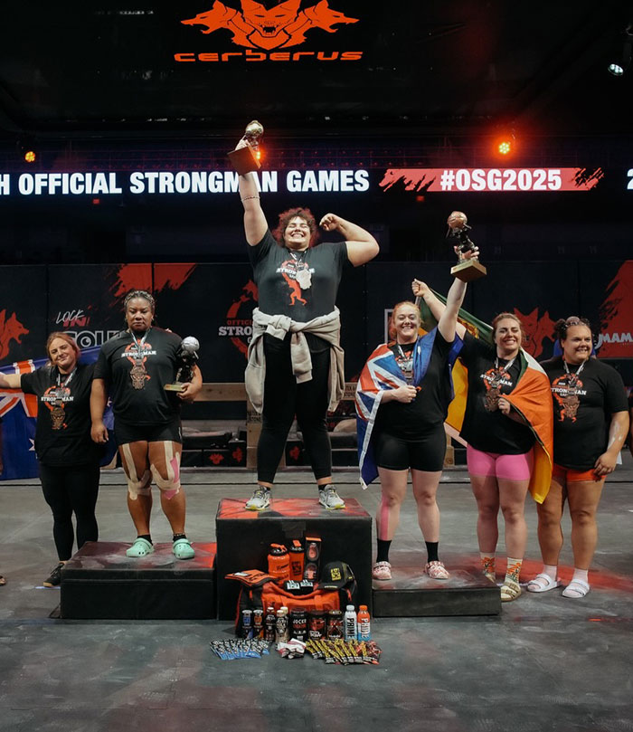Podium scene with strongwoman athletes celebrating at official strongman games event with trophies and medals. Podium scene with strongwoman athletes celebrating at official strongman games event with trophies and medals.